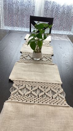 a wooden table topped with a potted plant on top of a black table cloth