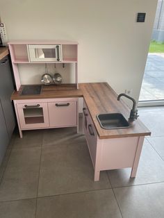 a kitchen with pink cabinets and wooden counter tops