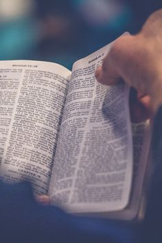 a person is holding an open book in their left hand and reading it with both hands