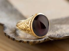 A beautiful signet ring with carvings on the sides made by hand and garnet gemstone in the center. *real images of the ring, taken by us* Garnet Stone Size: 14x12mm Material: - Sterling Silver 925 - 9K Gold (375) - 14K Gold (585) - 18K Gold (750) *All signet rings are hallmarked on the back for certification* - We offer FREE Worldwide DHL & FedEx Shipping! - Branded DanelianJewelry Gift Box with each order! Our customer service is available 7 days a week. Leave us your message, and we will get b Classic Carved Signet Ring For Formal Occasions, Heirloom Ruby Signet Ring With Hallmark, Antique Carved Signet Ring For Formal Occasions, Round Carved Engraved Ring For Formal Occasions, Formal Round Carved Engraved Ring, Antique Ruby Signet Ring, Antique Hallmarked Ruby Signet Ring, Vintage Garnet Rings With Polished Finish, Oval Garnet Signet Ring For Anniversary