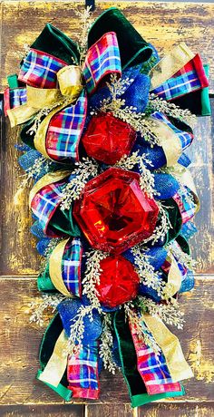 a christmas wreath with red, white and blue bows on it sitting on a wooden surface