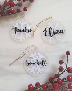 three personalized snowflake ornament hanging from twine with berries and twigs