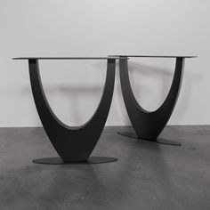 two black tables with curved bases on each side