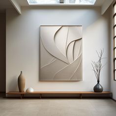 an abstract painting hangs on the wall next to two vases and a large window