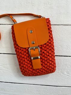 an orange purse sitting on top of a white wooden floor