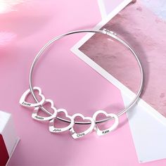 Celebrate the love and connection of family with this Custom Names Engraved Heart Charms Bangle Bracelet. Perfect for moms, grandmas, or anyone who cherishes their loved ones, this elegant bracelet features multiple heart-shaped charms, each engraved with a special name, making it a meaningful and timeless keepsake. Key Features: 💖 Personalized Heart Charms: Each heart charm can be engraved with a name, making this bracelet a unique way to honor family members, children, or grandchildren. ✨ Premium Bangle Design: The bracelet is made from high-quality [insert material, e.g., sterling silver, gold-plated], ensuring both durability and a polished, sophisticated look. 🎁 Perfect Gift for Moms & Grandmas: A thoughtful gift for Mother's Day, birthdays, anniversaries, or any occasion to celebra Bangle Bracelets With Charms, Mom And Grandma, Bangle Designs, Elegant Bracelet, Charm Bangle, Bracelet Bangle, Perfect Gift For Mom, Love Symbols, Heart Charm Bracelet