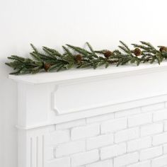 a white brick fireplace with pine cones and greenery