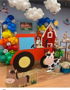 a room with balloons and farm animals on the floor, including a tractor in front of a barn