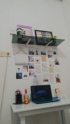 a laptop computer sitting on top of a desk next to a shelf filled with pictures