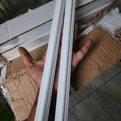 a hand is holding onto the side of an open window with cardboard on it and another person's hand reaching out