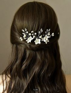 a woman with long brown hair wearing a white flower and leaf bridal headpiece