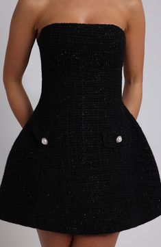 a woman wearing a black dress with buttons