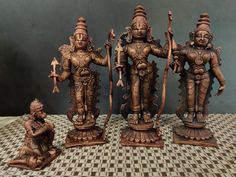 three bronze figurines sitting on top of a checkered table cloth