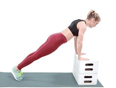 a woman doing push ups on top of a white box with red leggings