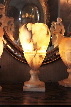 three marble vases sitting on top of a wooden table next to a round mirror