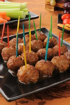 several skewered meatballs with toothpicks in them on a black plate