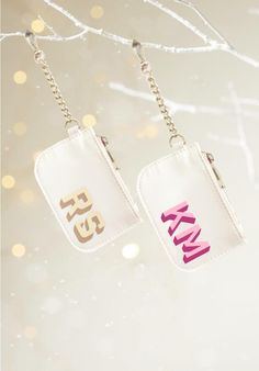 two keychains with the word km and k on them hanging from a tree