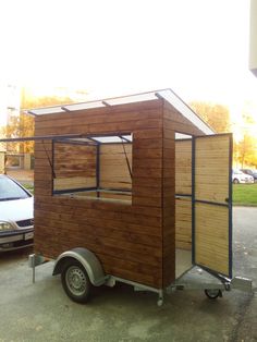 a small wooden building sitting on top of a parking lot next to a white car