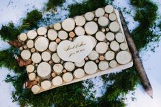 a wedding cake made out of wooden slices with a heart on the top, surrounded by greenery