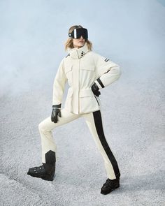 a woman in white and black ski suit posing for a photo with snowboard boots