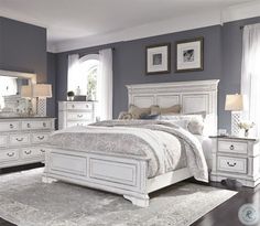 a white bed sitting on top of a hard wood floor next to a dresser and mirror