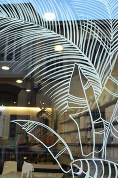 the reflection of a palm tree in a glass window with an animal figurine behind it