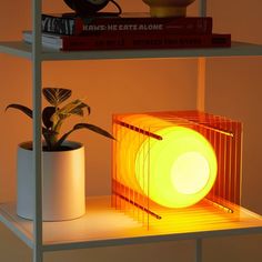 a yellow lamp sitting on top of a shelf next to a potted plant