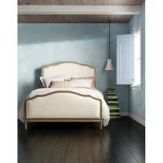 a white bed sitting on top of a hard wood floor next to a lamp and window