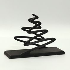 a black object with a spiral design on it's base, sitting on a white surface