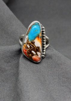 "Unique Ladies Spiny Oyster and Turquoise Combination Sterling Silver Ring Top: 23 mm x 14 mm; 7/8\" x 1/2\" Weight: 6.1 Grams US Size 10. Can be Resized at no Additional Cost 925 Silver Color patterns may vary slightly. $75 . Exclusively Designed by Richard James for Richlo Jewelry Check out our other fine jewelry at: https://etsy.com/shop/arizonagemstudio In life, Spiny Oyster shells had some very imposing \"quills\" which could be used for camouflage or protection from other species. Interest Richard James, Oyster Shells, Green Valley, Spiny Oyster, 925 Silver Ring, 925 Silver Rings, Turquoise Sterling Silver, Handmade Ring, Handmade Silver