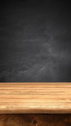 an empty wooden table in front of a chalkboard