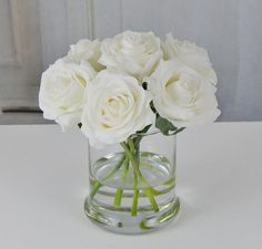 white roses in a glass vase on a table