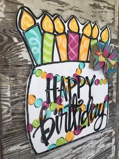 a happy birthday sign hanging on the side of a wooden door with candles in it