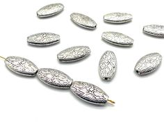 several silver colored beads with designs on them are arranged in the shape of oval shapes