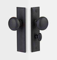 two black door knobs on the side of a white wall and one has an oval handle