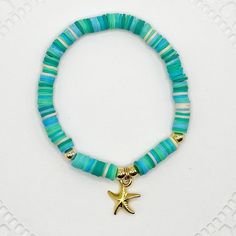 Embrace the essence of the ocean with this Tropical Starfish Bracelet. This stunning piece is crafted with vibrant turquoise and aqua beads, accented with a gold starfish charm that captures the spirit of the sea. Perfect for beach lovers, summer outfits, or anyone looking to add a touch of tropical charm to their jewelry collection. Details: *Materials: High-quality turquoise and aqua vinyl disc beads, gold starfish charm, and gold accent beads. *Length: 7 inches on elastic cord allowing stretc Adjustable Blue Jewelry With Starfish Charm, Adjustable Turquoise Jewelry With Star Charm, Adjustable Blue Starfish Jewelry, Turquoise Beaded Bracelets With Starfish Charm, Bohemian Turquoise Starfish Beaded Bracelets, Bohemian Blue Starfish Charm Jewelry, Bohemian Blue Jewelry With Starfish Charm, Blue Bracelets With Starfish Charm And Round Beads, Adjustable Blue Bracelets With Starfish Charm