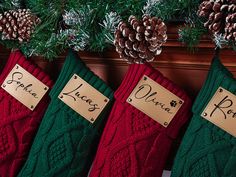 three christmas stockings with name tags and pine cones hanging from the mantle in front of them