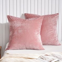 two pink pillows sitting on top of a bed