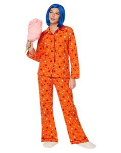 a woman in an orange polka dot pajama set holding a pink rose