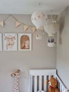 a baby's room with a crib, stuffed animals and pictures on the wall