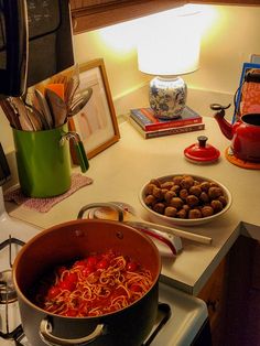 a pot filled with pasta and meatballs on top of a kitchen counter next to a stove