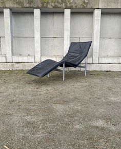 an empty lounge chair sitting in front of a concrete wall