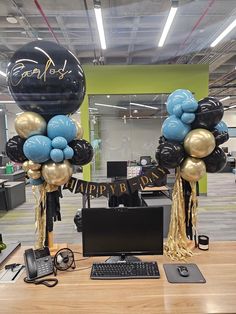 balloons and streamers are on display in an office cubicle with a computer keyboard