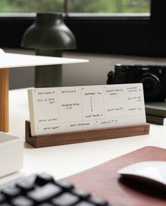 a desk with a keyboard, mouse and business card holder on it's side