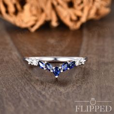 a diamond and blue sapphire ring sitting on top of a wooden table