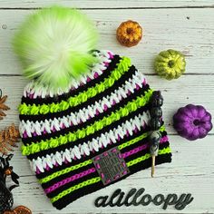 a knitted hat with green, white and black stripes next to other crochet items