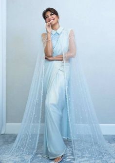 This beautiful sari set has a crystal embellished high neck blouse with a sari and cape embellished with crystals. Eid Saree With Sheer Dupatta And Cape Sleeves, Pre-draped Saree With Cape Sleeves For Eid, Bollywood Pre-draped Saree With Sheer Dupatta And Cape Sleeves, Designer Lehenga With Pearl Embroidery And Cape Sleeves, Designer Sets With Pearl Embroidery And Cape Sleeves, Bollywood Saree With Cape Sleeves For Designer Wear, Bollywood Saree With Cape Sleeves And Dupatta, Festive Party Wear Saree With Cape Sleeves, Evening Saree With Pearl Embroidery