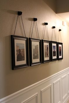 four framed pictures hanging on the wall in a hallway with white wainscoting