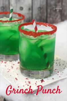 two glasses filled with green liquid and red sprinkles sitting on top of a white plate