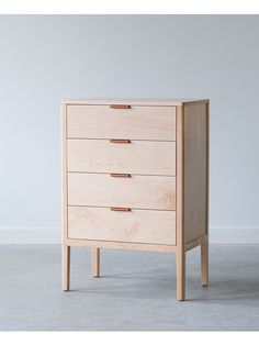 a wooden chest of drawers sitting on top of a cement floor next to a white wall